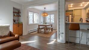 Una cocina moderna con comedor, suelo de madera y una lámpara colgante.