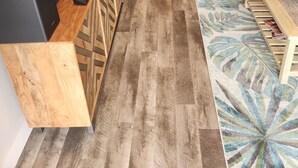 Un salon moderne avec un téléviseur à écran plat, des meubles en bois, un canapé et un tapis à motifs.
