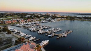 Un port de plaisance où de nombreux bateaux sont amarrés aux quais, entouré d’immeubles résidentiels et offrant une vue lointaine sur les gratte-ciel d’une ville.