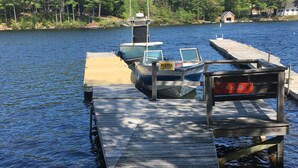 A wooden dock extending into a lake with boats moored at the end. - Kettle Cove in Sebago Lake, Maine (Casco)