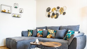 A modern living room with a grey sofa, colorful cushions, and a decorative wall piece. - Zentral Gelegenes 55 m² Design-apartment (Magdeburg)