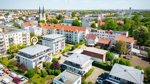 An aerial view of a residential area with multiple apartment buildings, a church spire, and a clear sky. - Zentral Gelegenes 55 m² Design-apartment (Magdeburg)