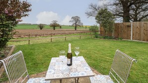 A patio with a table set for two, a bottle of wine, and two glasses. - Bee Happy Barn (Norwich)