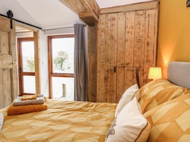 Un dormitorio con cama, un armario de madera, una ventana con cortinas y una lámpara.