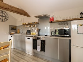 Una cocina moderna con electrodomésticos de acero inoxidable, una viga de madera en el techo y un reloj en la pared.