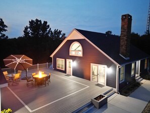 A house with a deck, a fire pit, and a large umbrella.