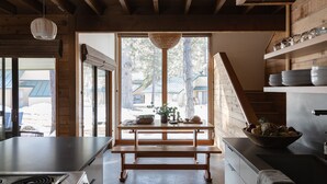 A modern kitchen with a wooden bench, a large window, and a bowl of fruit on the counter. - Cozy Ranch Retreat with Access to The Cove (Sunriver)