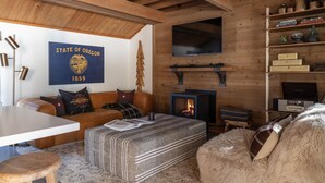 A cozy room with a wooden ceiling, a sofa, a table, and a fireplace. - Cozy Ranch Retreat with Access to The Cove (Sunriver)