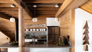 A kitchen with wooden beams, a stainless steel refrigerator, and a bar area with stools. - Cozy Ranch Retreat with Access to The Cove (Sunriver)