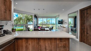 A modern kitchen with a large island, wooden cabinets, and a view of the outdoors. - Luxury 5* 3 bdr Oceanfront condo between both Eagle & Palm Beach! (Oranjestad)