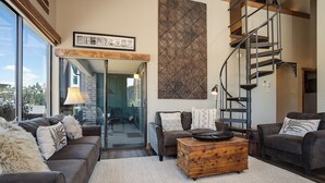 A modern living room with a spiral staircase, a large window, and a fireplace.