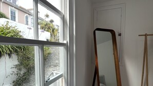 Una habitación con un ventanal amplio, un espejo y una cama.