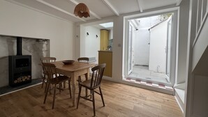 Un comedor con mesa y sillas de madera, una pared de piedra con chimenea, y vistas a un espacio exterior a través de un ventanal.