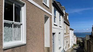 Una calle estrecha con casas escalonadas, vista despejada al mar y una isla distante.