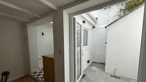 Un interior moderno con suelo de madera, un felpudo a cuadros y vistas a un espacio exterior a través de un ventanal.