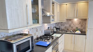 A modern kitchen with a gas stove, microwave, toaster, and a sink.