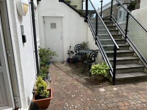 A courtyard with a staircase, potted plants, and outdoor furniture. - Penryn a modern spacious ground floor apartment (St Ives)
