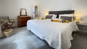 Una camera da letto con un letto grande, una cassettiera, uno specchio e una lampada.
