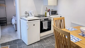 Una cucina compatta con forno a incasso, microonde e macchina per il caffè.