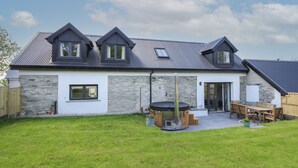A modern house with a stone facade, a large patio with outdoor furniture, and a covered outdoor seating area.