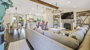 A spacious living room with a large beige sectional sofa, a fireplace, and a dining area with a wooden table and chairs.