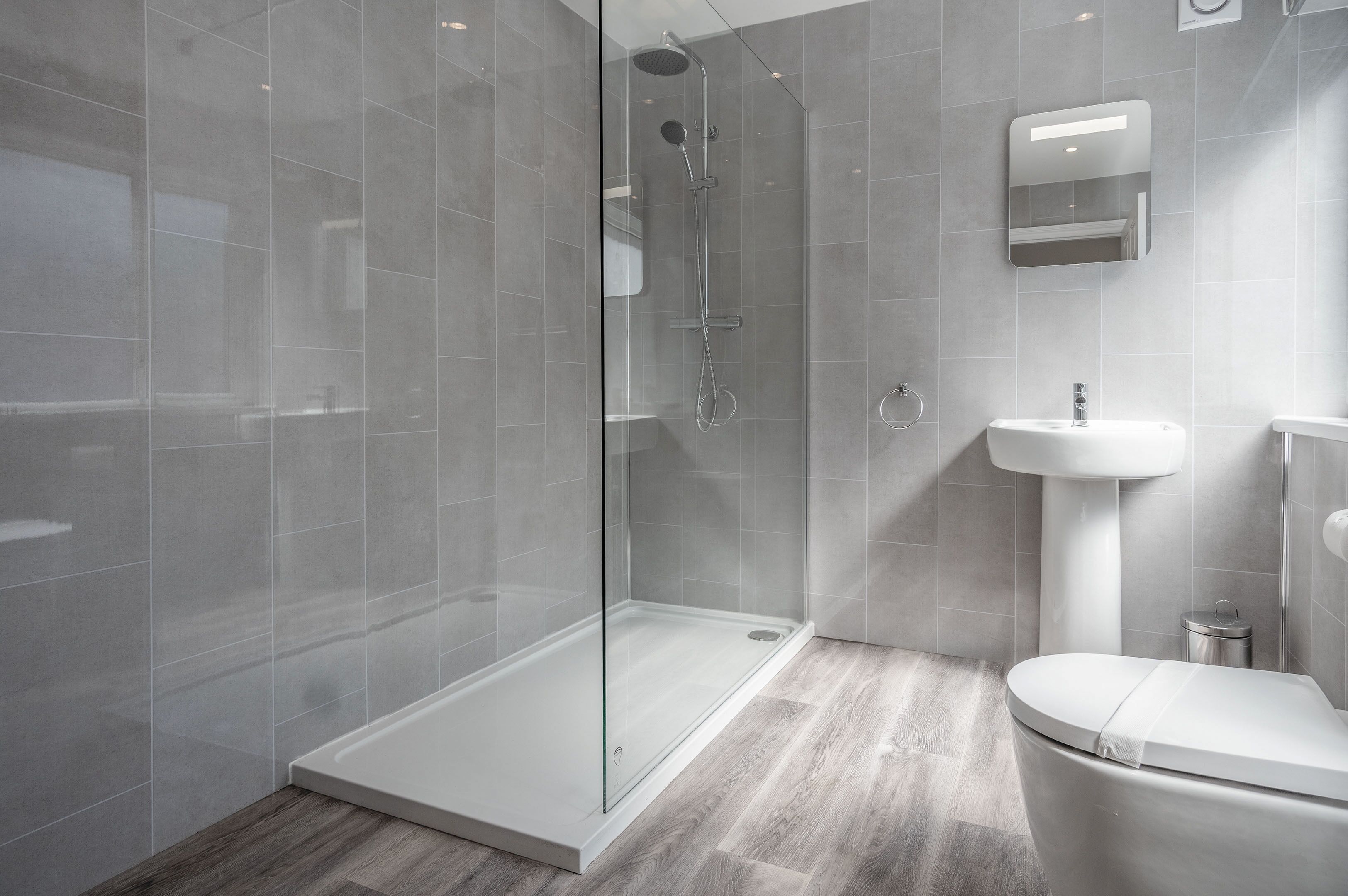 A modern bathroom with a glass-enclosed shower, a white sink, and a toilet.