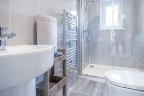 Um banheiro moderno com pia branca, box de vidro e vaso sanitário.