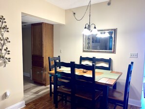 A dining area with a wooden table and chairs, a chandelier, and a mirror on the wall.