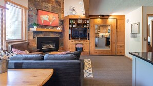 A cozy living room with a fireplace, a TV, and a dining area. - Iron Horse C5013 Condo by RedAwning (Winter Park)