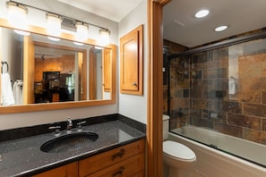 A bathroom with a black sink, wooden cabinets, a large mirror, and a glass-enclosed shower. - Iron Horse C5013 Condo by RedAwning (Winter Park)