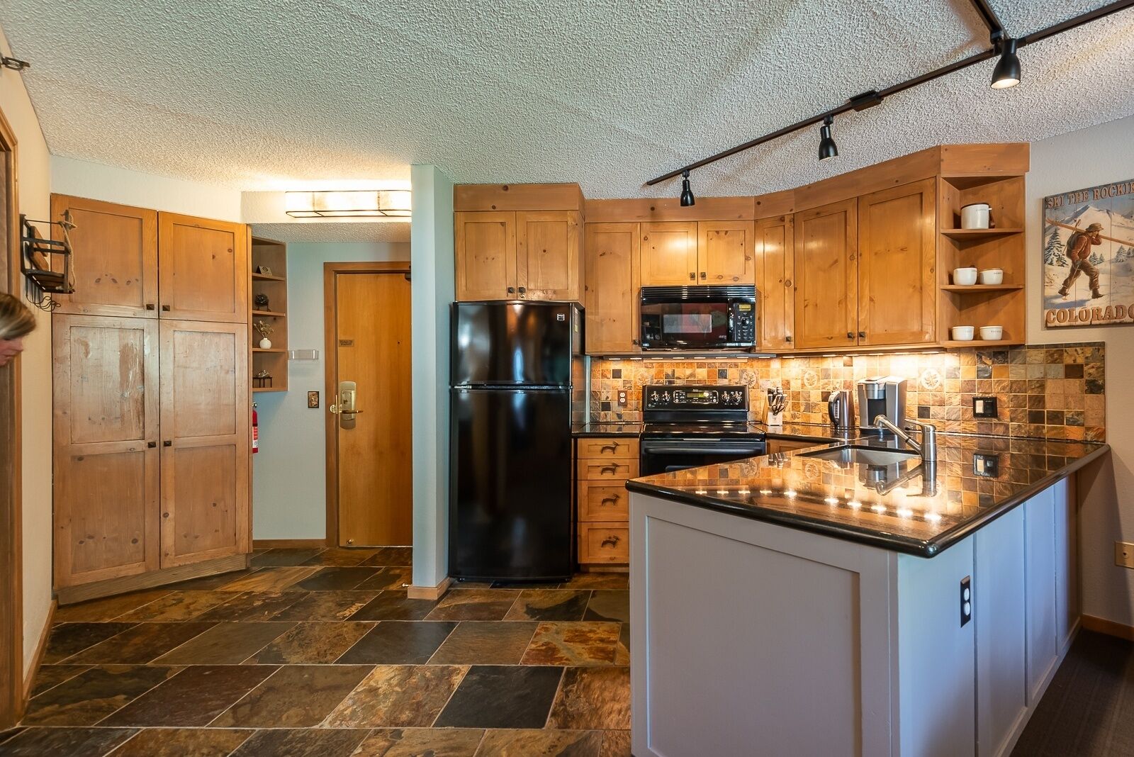 A kitchen with wooden cabinets, a black refrigerator, a microwave, and a stove.