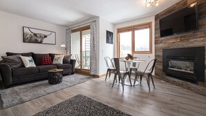 A modern living room with a dark sofa, a round coffee table, and a fireplace. - Iron Horse C3013 Condo by RedAwning (Winter Park)