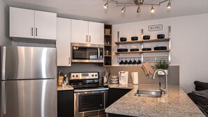 A modern kitchen with stainless steel appliances, a built-in oven, and a breakfast bar area. - Iron Horse C3013 Condo by RedAwning (Winter Park)