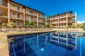 A multi-story hotel with a swimming pool, outdoor seating, and a clear blue sky. - Kihei Ali'i Kai D201 1 Bedroom Condo (Kihei)