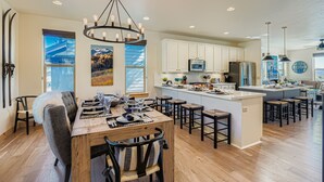 A modern kitchen with a central island, wooden flooring, and pendant lighting.