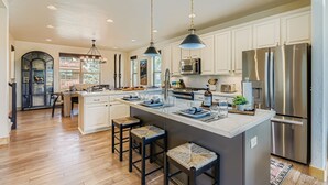 A spacious kitchen with white cabinets, stainless steel appliances, and a large island with stools.