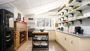 Eine moderne Küche mit Kamin aus Backsteinen, einem Herd, einer Spüle und einem Essbereich mit Tisch und Stühlen.