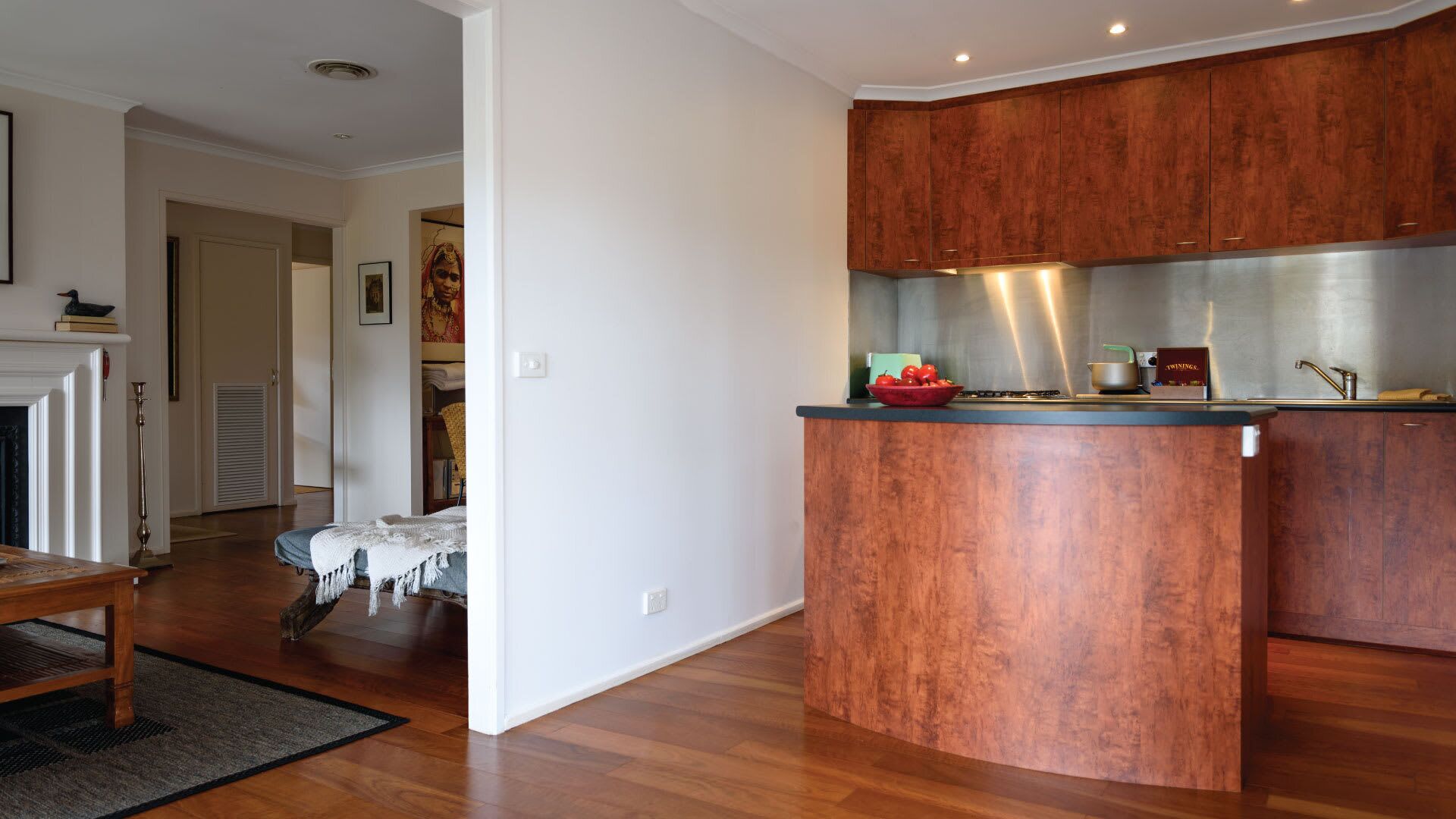 A modern kitchen with wooden cabinets, a built-in island, and a dining area with a table and chairs.