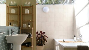 A bathroom with a sink, shelves, a potted plant, and a shower area. - Wyuna (Hepburn Springs)