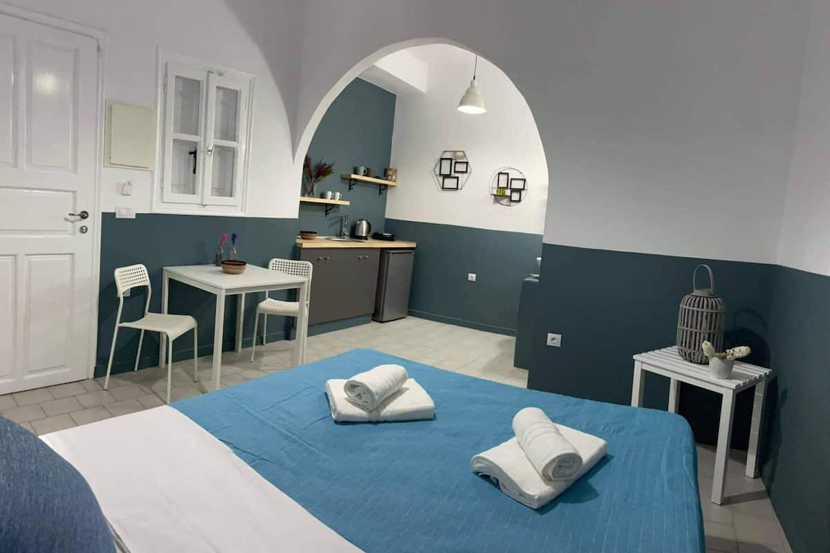 A compact hotel room with a bed, a desk, and a kitchenette.