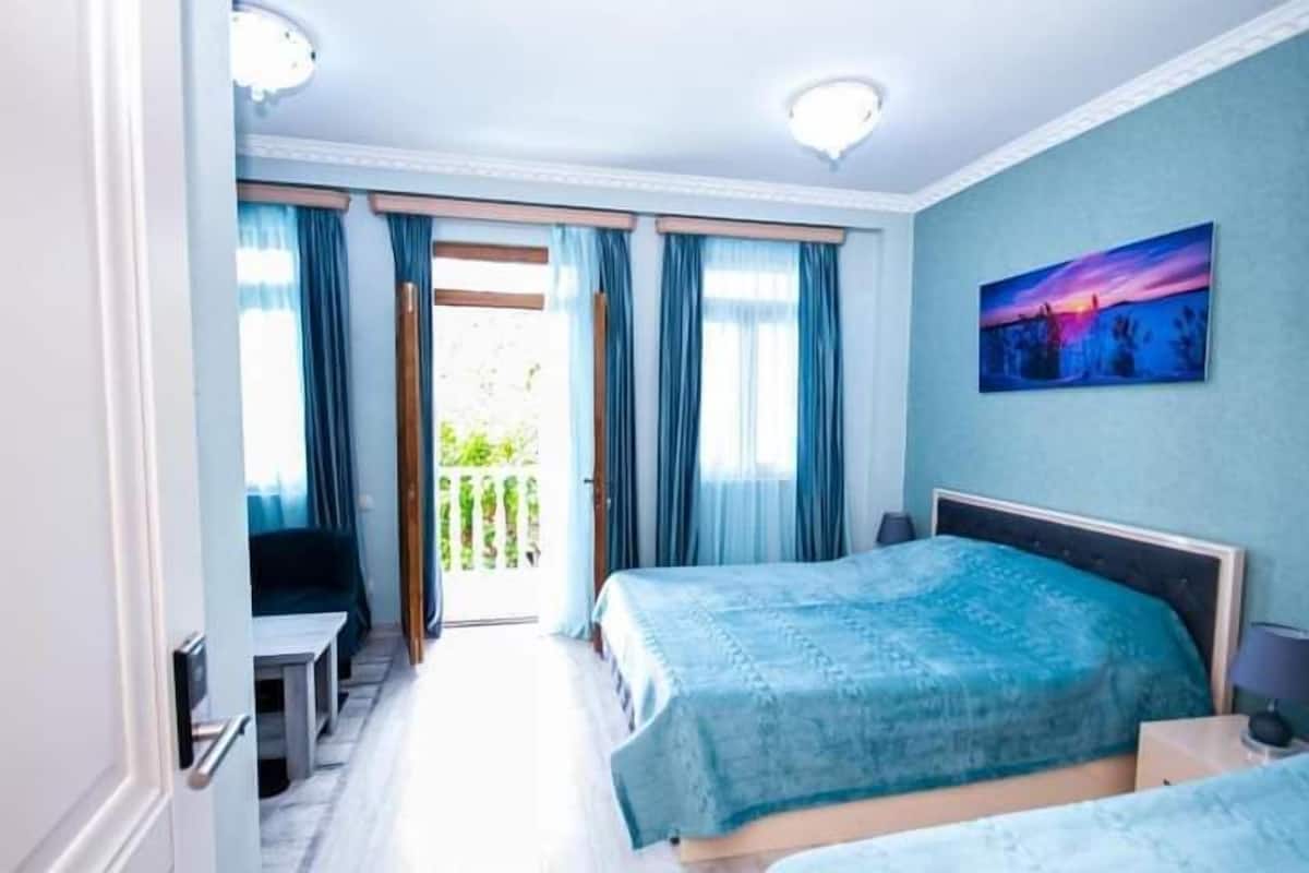 A hotel room with a bed, a desk, and a balcony.