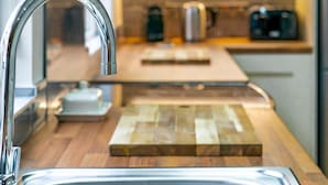 Una cocina moderna con un grifo de acero inoxidable, una tabla de cortar de madera y un microondas en la encimera.