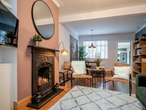 Una sala de estar acogedora con chimenea, un comedor y un sillón verde.