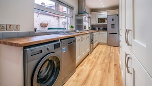 Una cocina moderna con lavadora integrada, electrodomésticos de acero inoxidable y encimera de madera.
