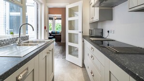 A modern kitchen with a large island, stainless steel sink, and a microwave. - Beautiful 4BR Restored Red Brick Cafes and  Park - Pass the Keys (Belfast)