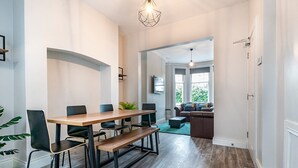 A modern dining area with a wooden table and chairs, a bench, and a hanging light fixture. - Beautiful 4BR Restored Red Brick Cafes and  Park - Pass the Keys (Belfast)