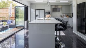A modern kitchen with a central island, built-in appliances, and a large window overlooking a garden.