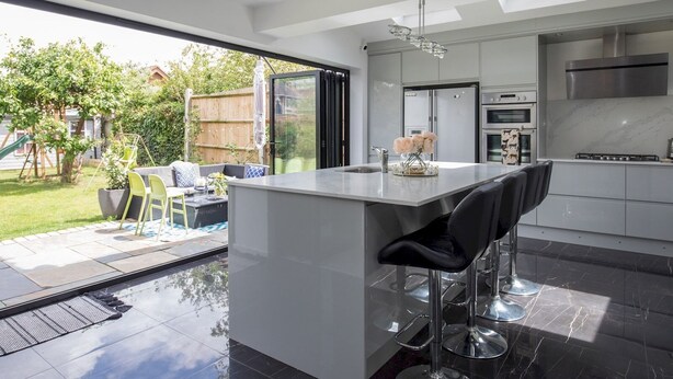 A modern kitchen with a large island, stainless steel appliances, and a sliding glass door to the backyard.