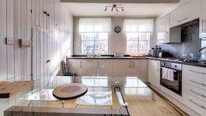 A modern kitchen with a dining area, large windows, and a view of buildings outside. - Modern Royal Mile 2 bed Flat Edinburgh - Pass the Keys (Edinburgh)