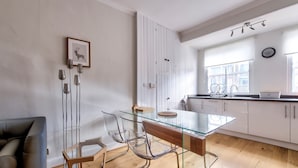 A modern kitchen with a glass dining table, white cabinets, and a wooden floor. - Modern Royal Mile 2 bed Flat Edinburgh - Pass the Keys (Edinburgh)